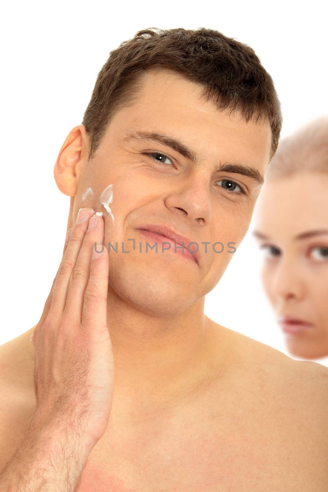 Happy man after shaving applying moisturizing cream upon his face