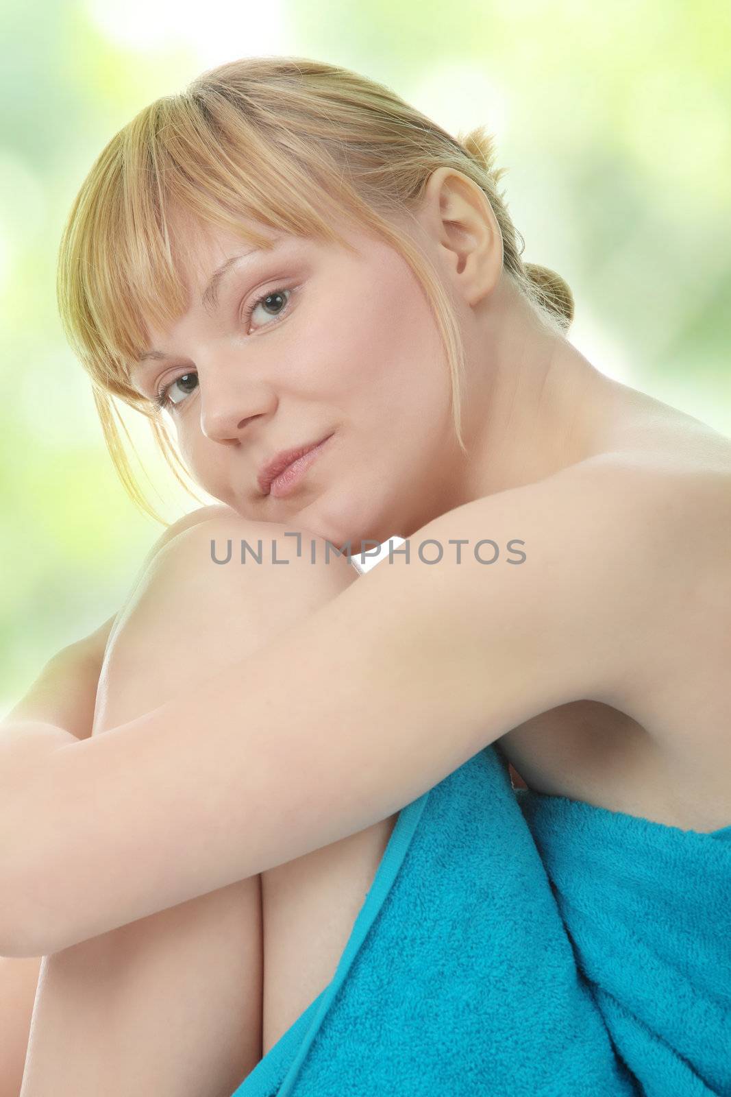 Attractive young nude woman getting ready for spa treatment, against abstract green background