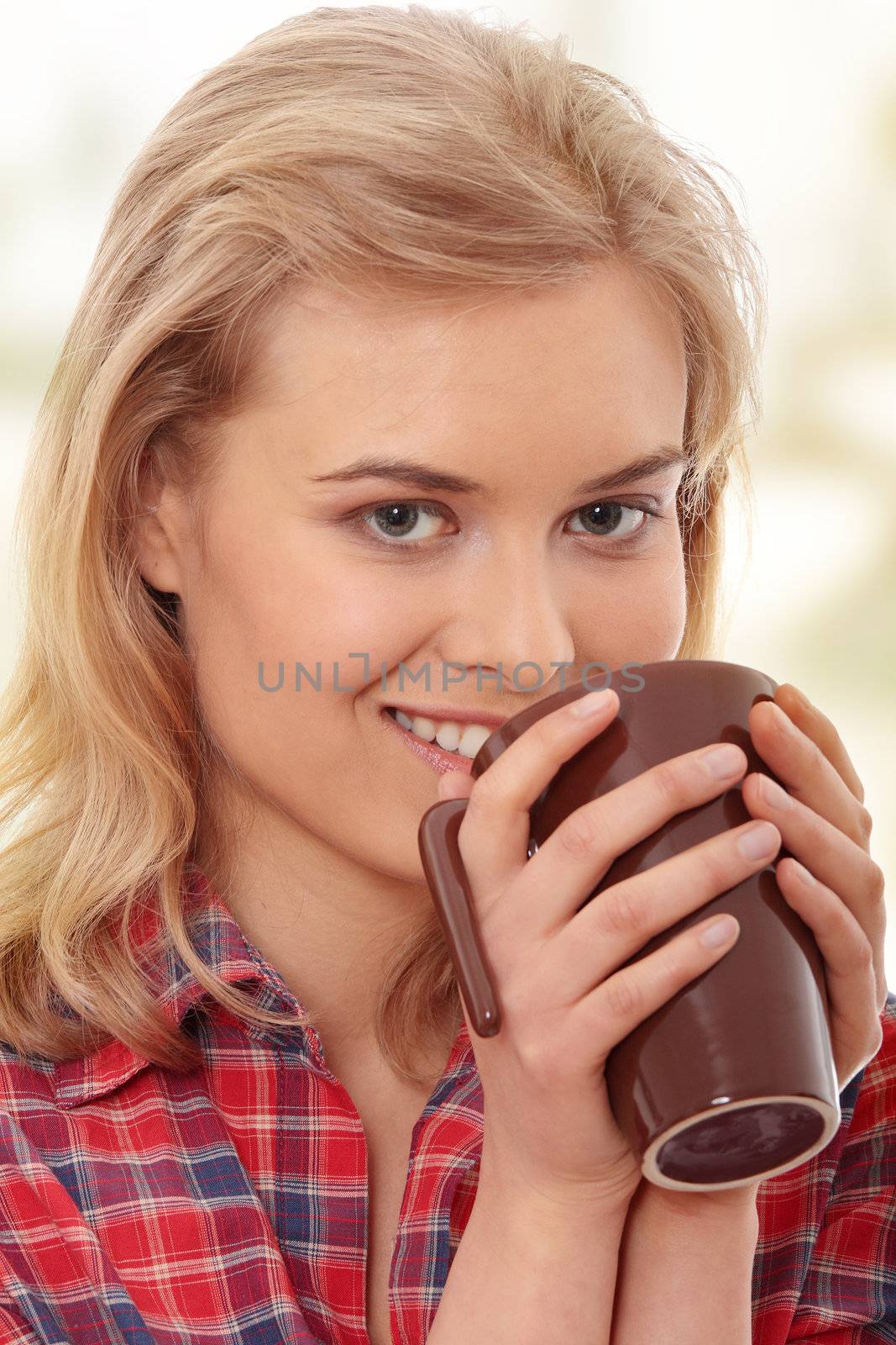 The beautiful young woman drinks morning coffee or tea