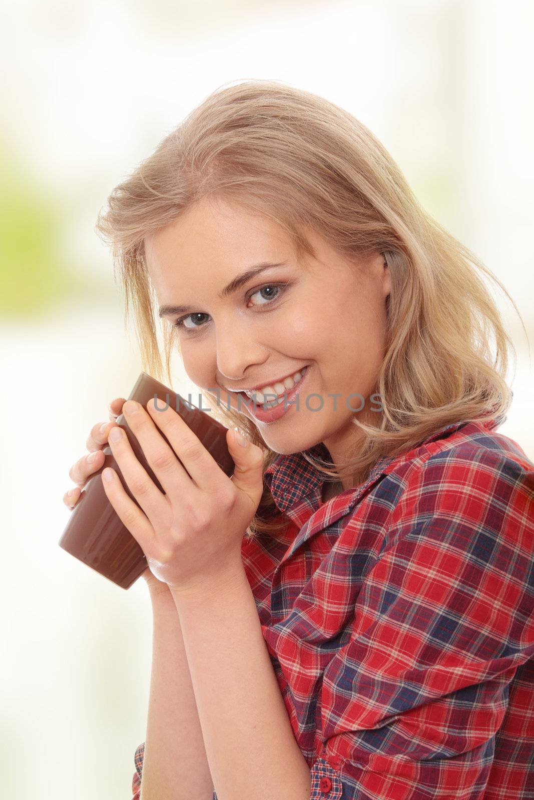 The beautiful young woman drinks morning coffee or tea