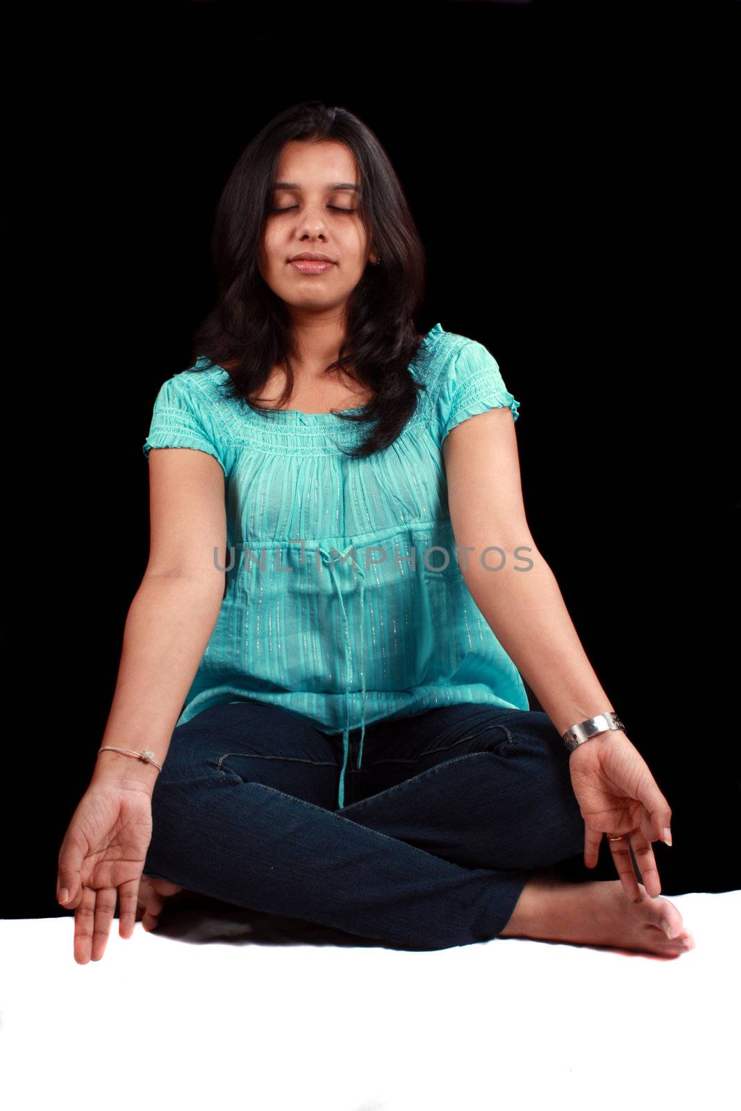 A beautiful Indian lady in meditation, on black background.