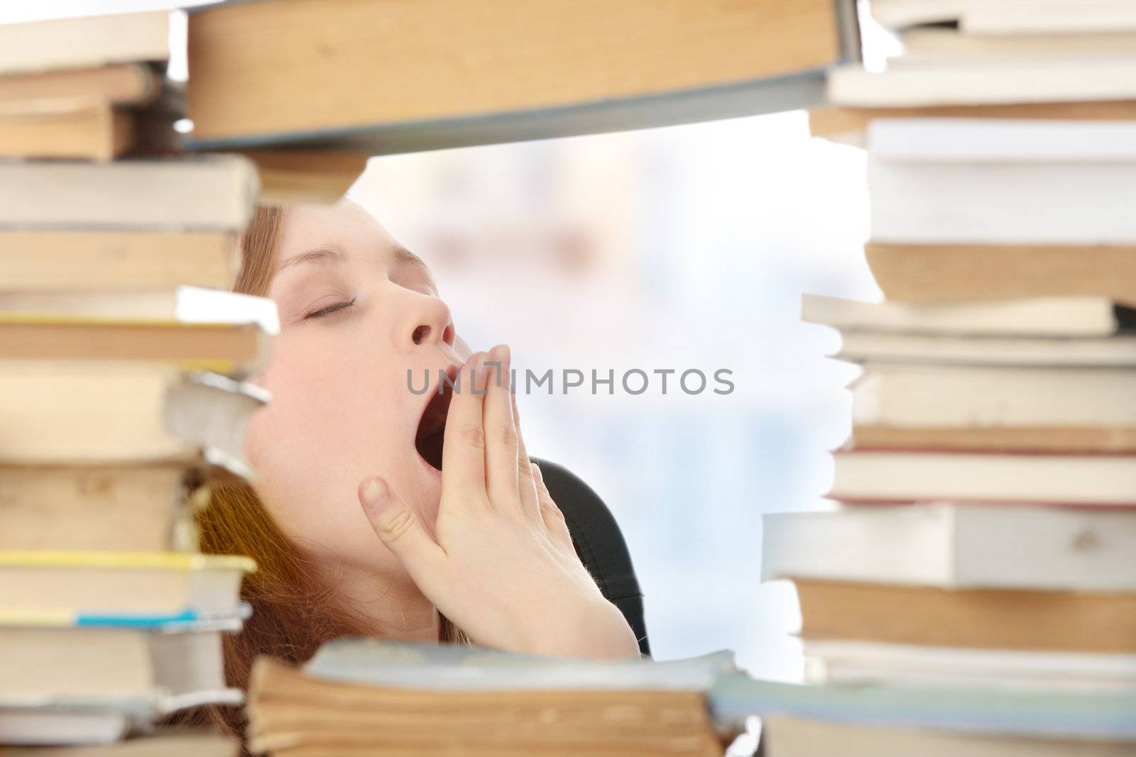 Young woman sitting behind books - tired