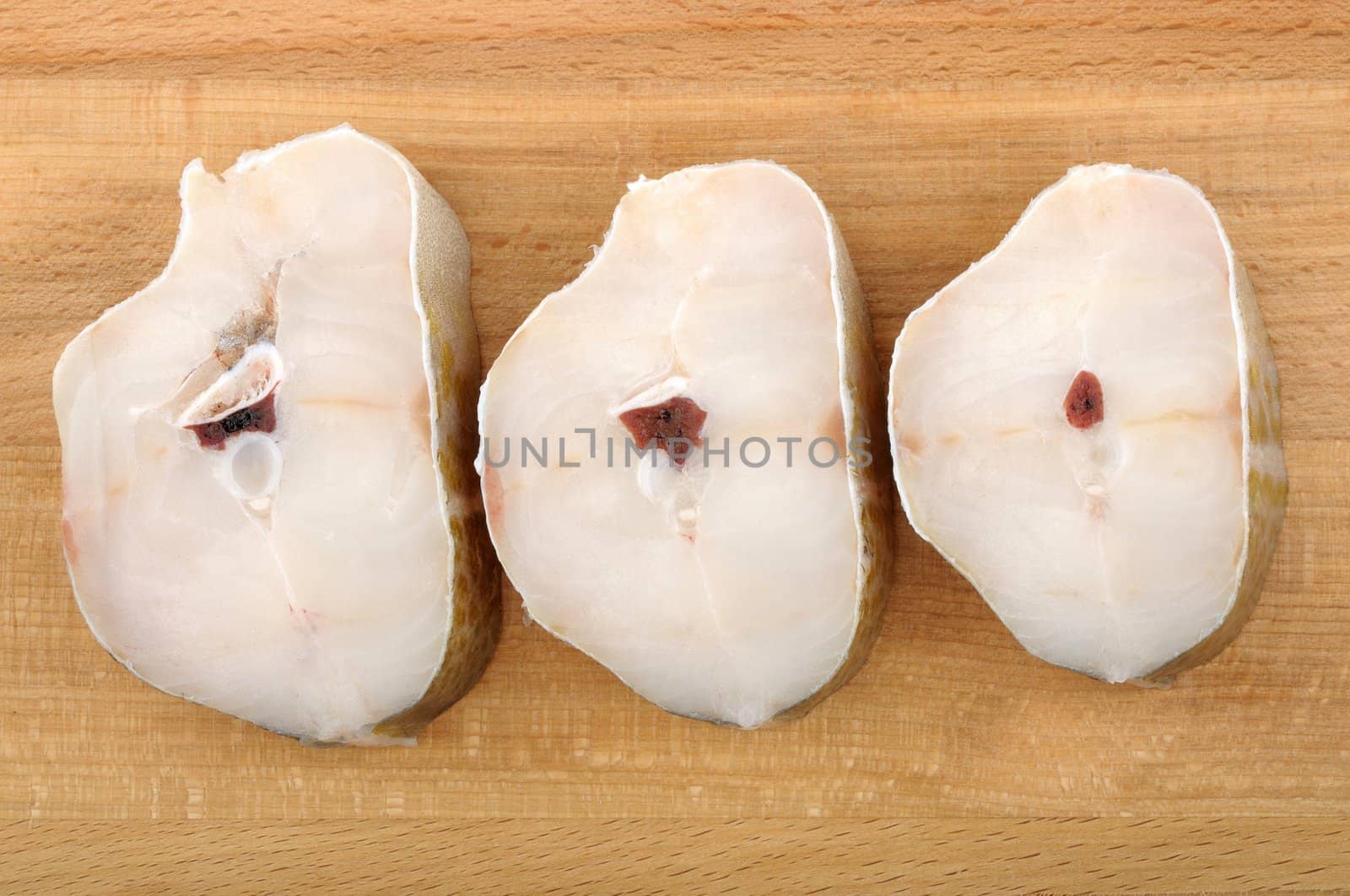 steaks of cod on a wooden cutting board