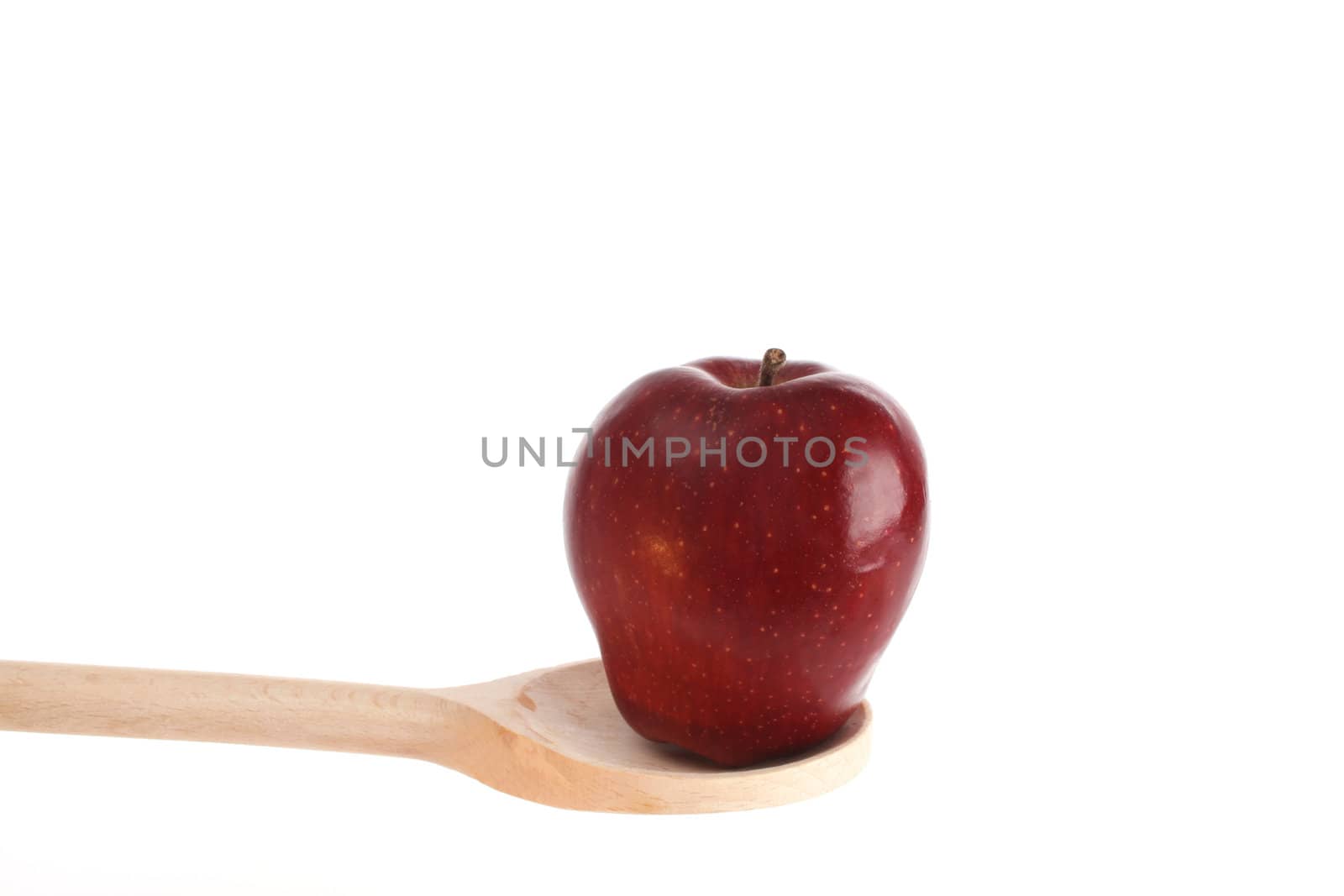 Apple on a wooden spoon isolated against a white background