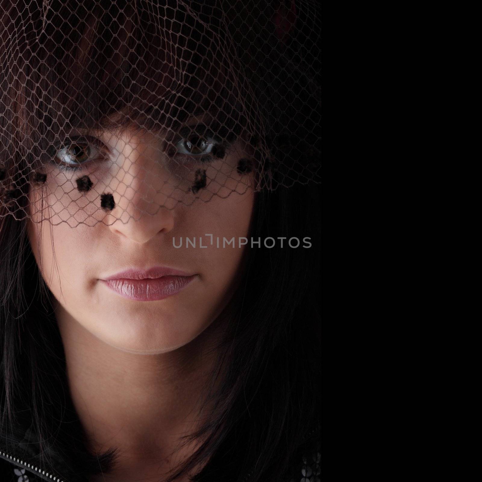 Beautiful young woman with long healthy dark hair on dark black background.