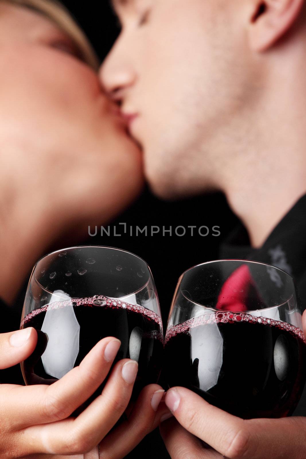Men, women and red wine. Black background