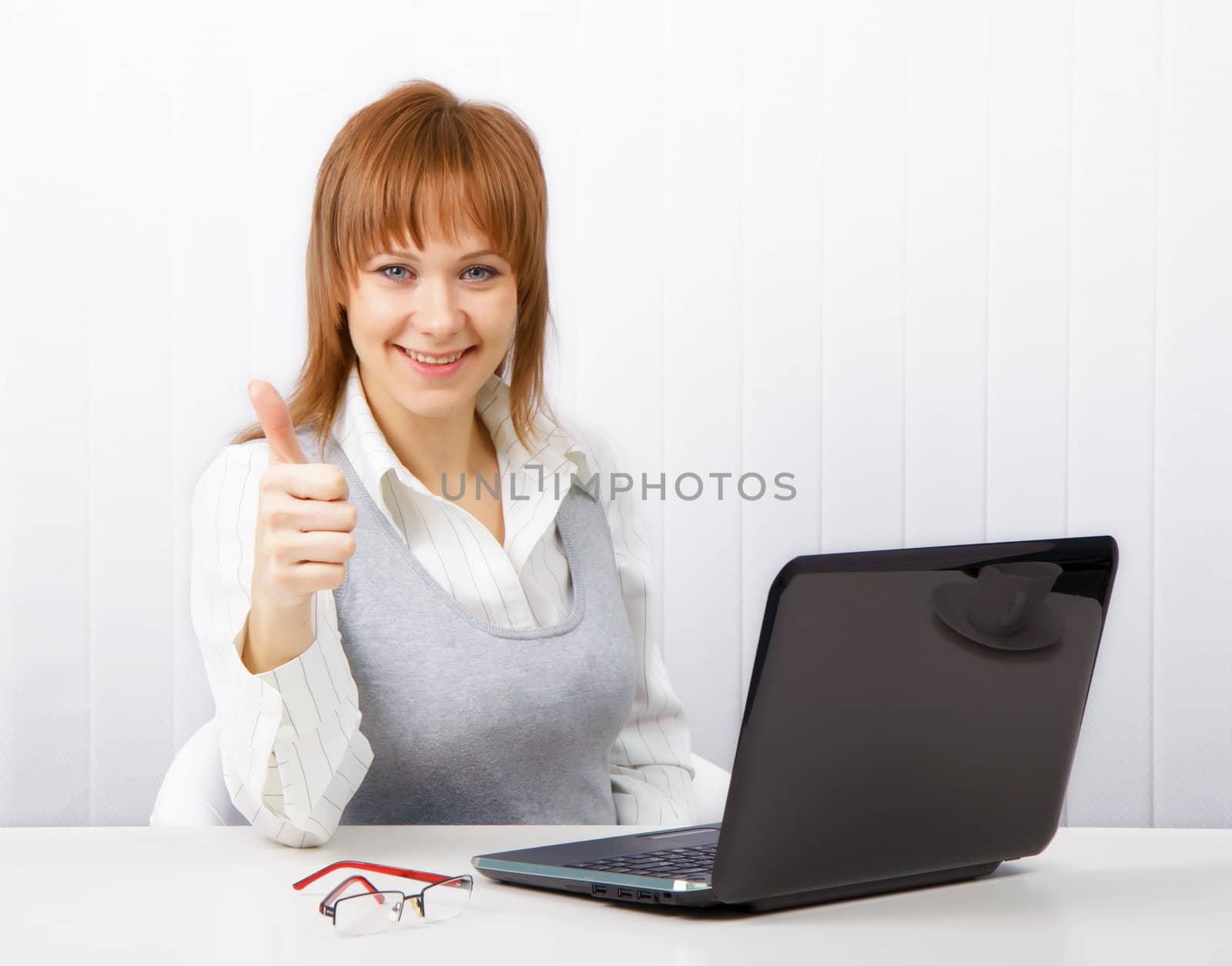 Positive smiling businesswoman with a laptop with a thumb up
