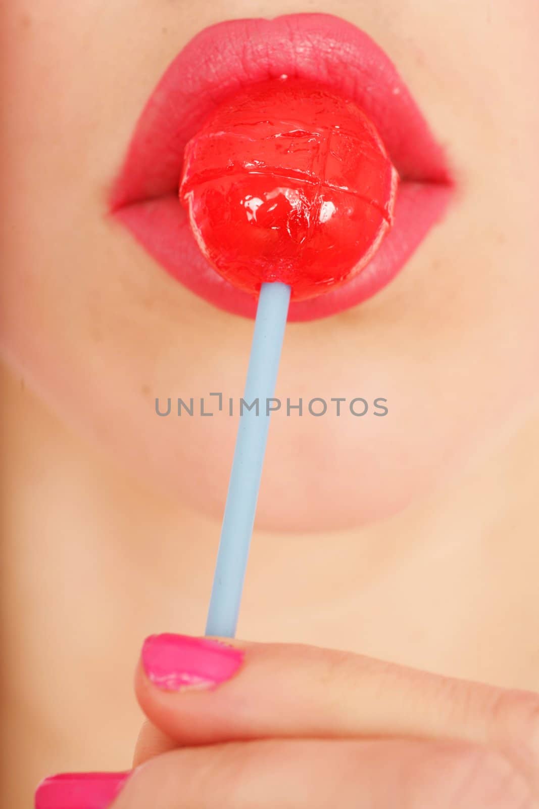 close-up of a red lollipop on pink lips