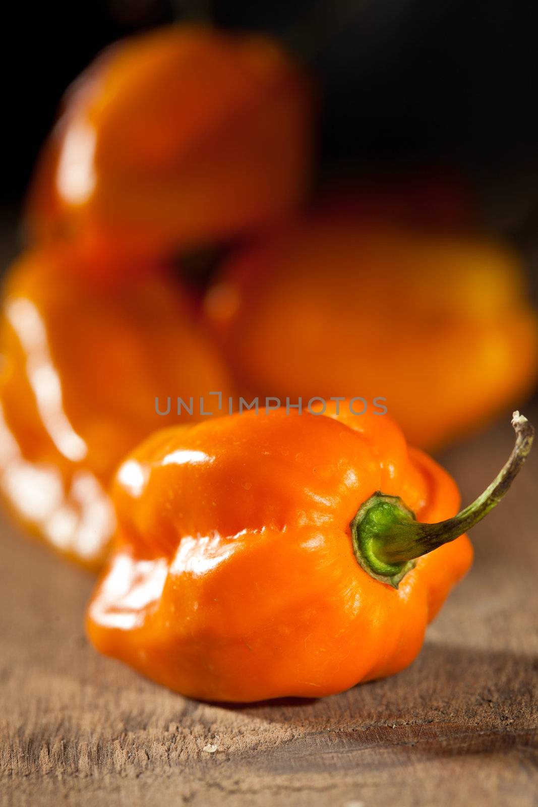 Small orange hot peppers on wooden background