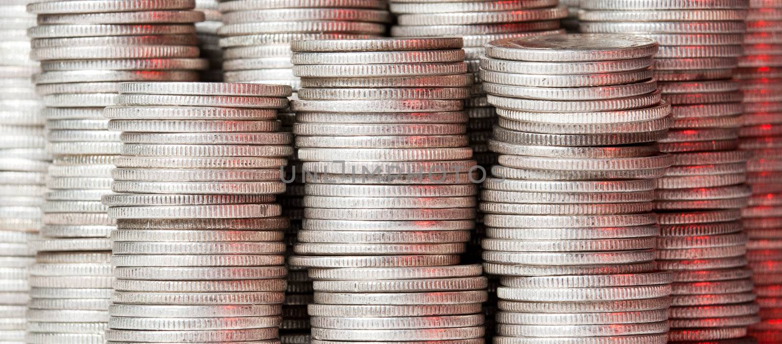 Many stacks of old silver dimes face on to camera and illuminated with red light