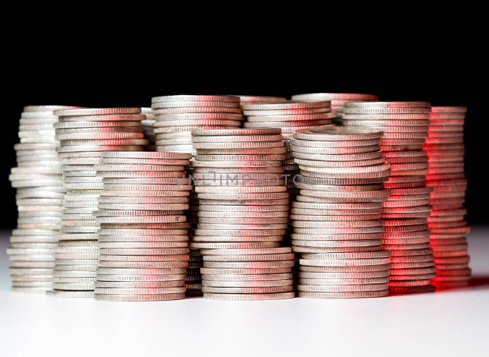 Many stacks of old silver dimes face on to camera and illuminated with red light