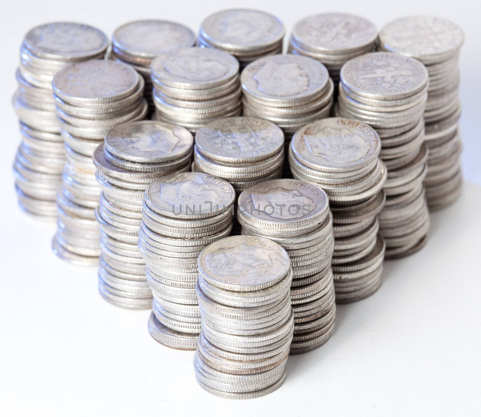 Many stacks of old silver dimes face on to camera and illuminated with blue light