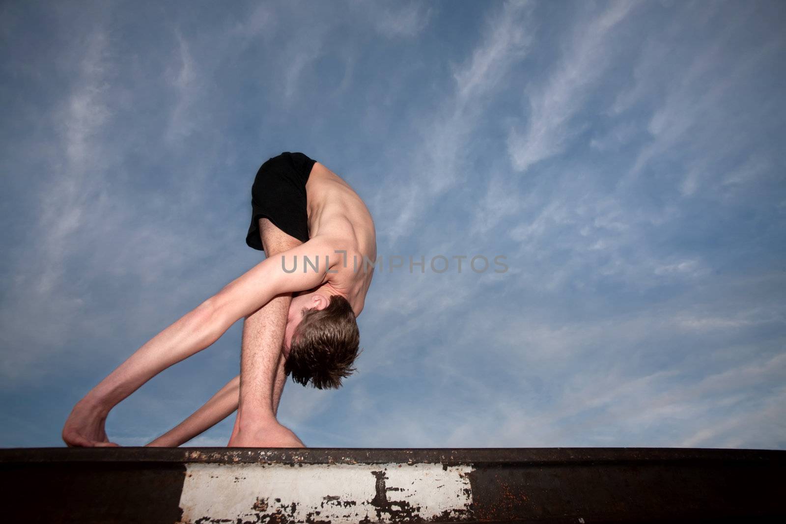 Extremely flexible yoga practitioner outside on rail track