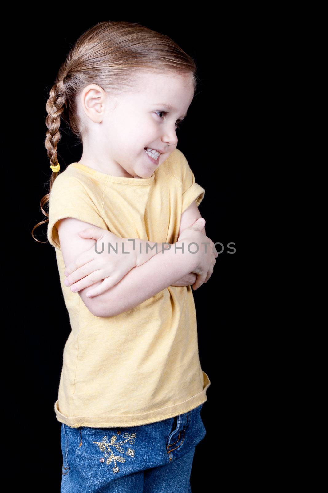 A girl with her arms crossed across her chest, she looks shy and aprehensive.