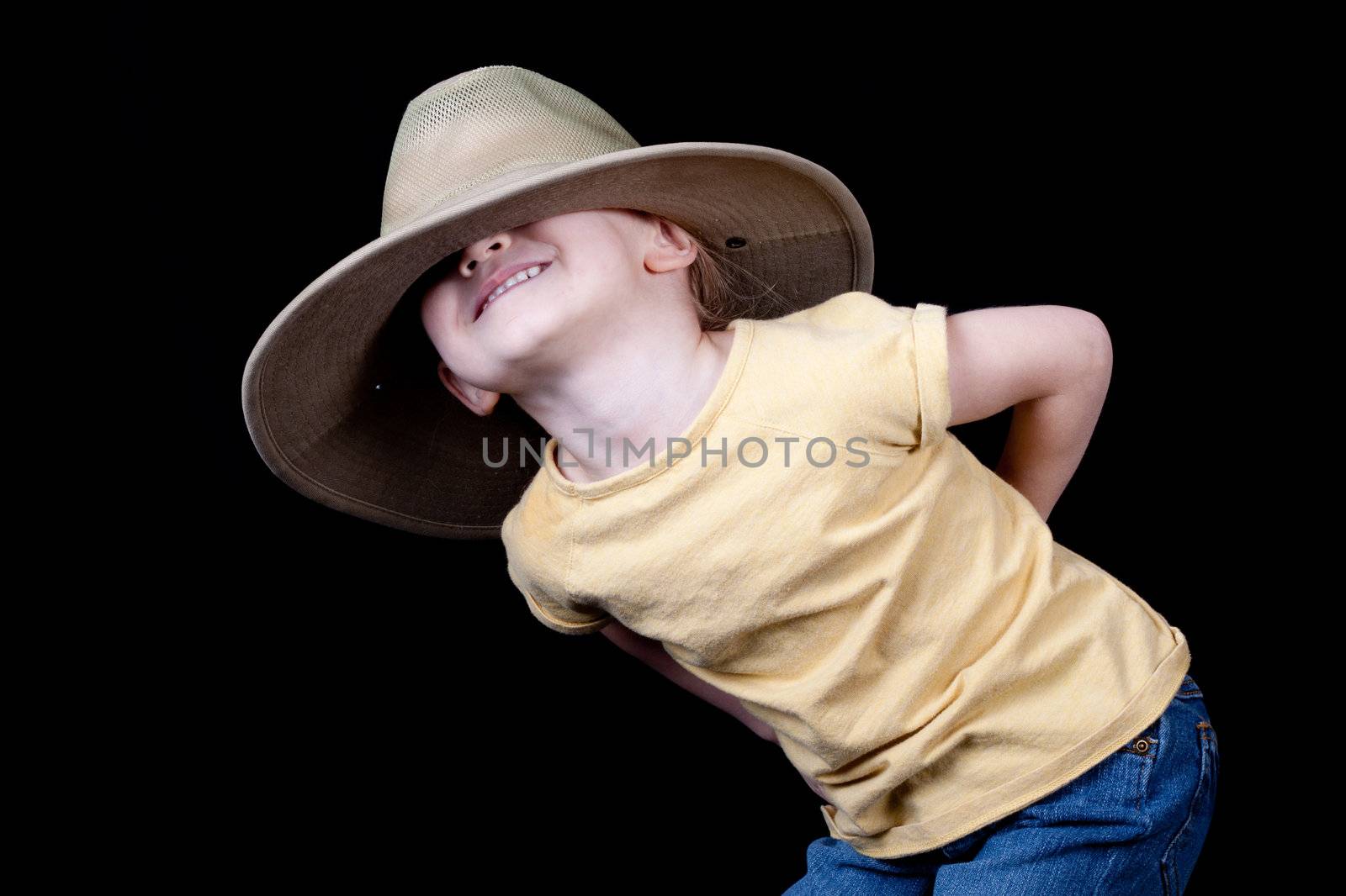 A cute girl with an oversized hat on her head.  It is pulled over her eyes.