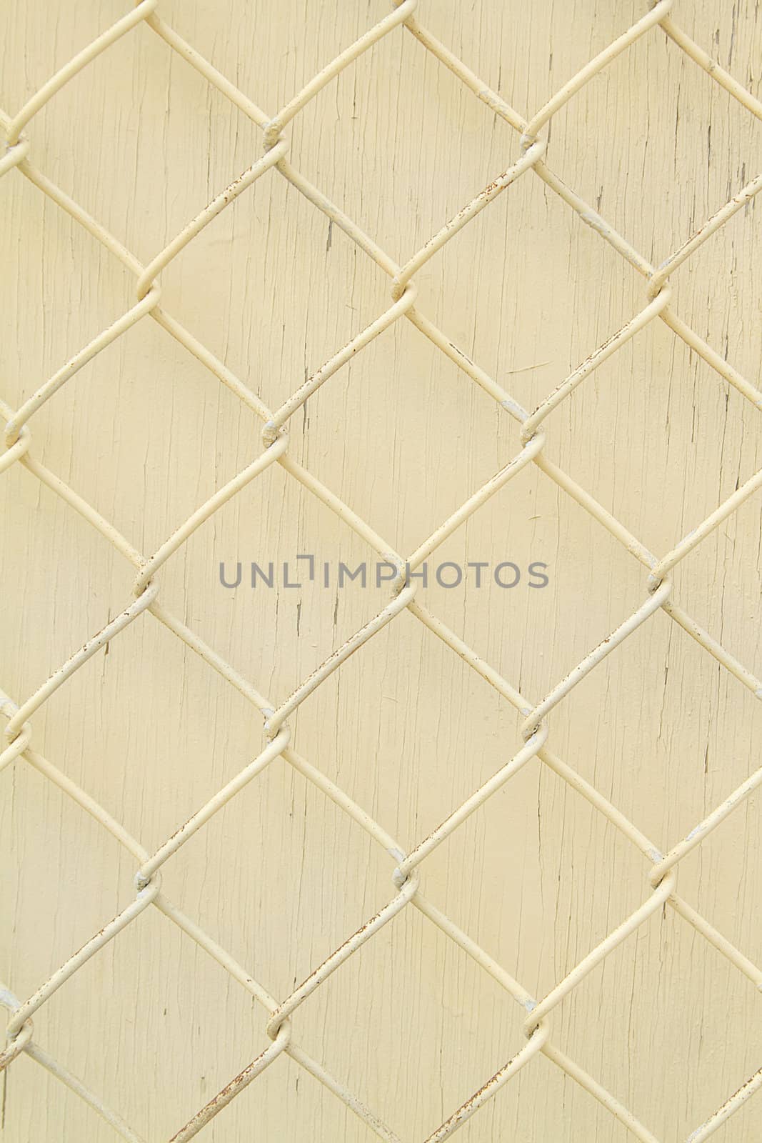 Yellow painted metal fence with yellow wooden background