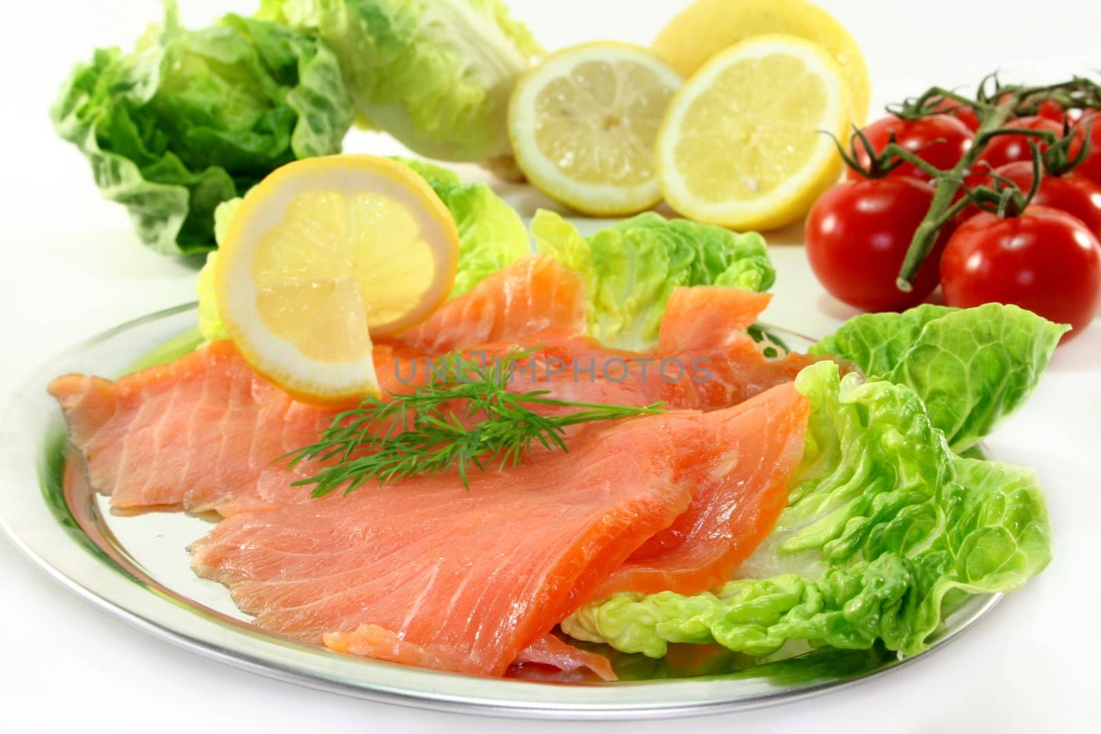 Salmon with lemon slices and dill on green salad