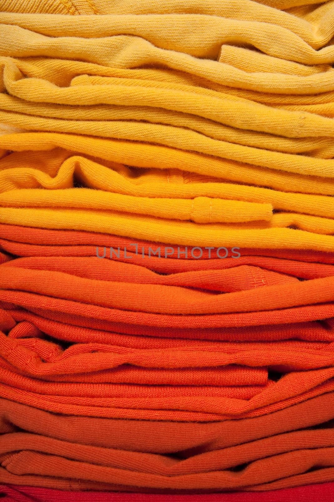 Warm colors background. Folded red, orange and yellow clothes. 