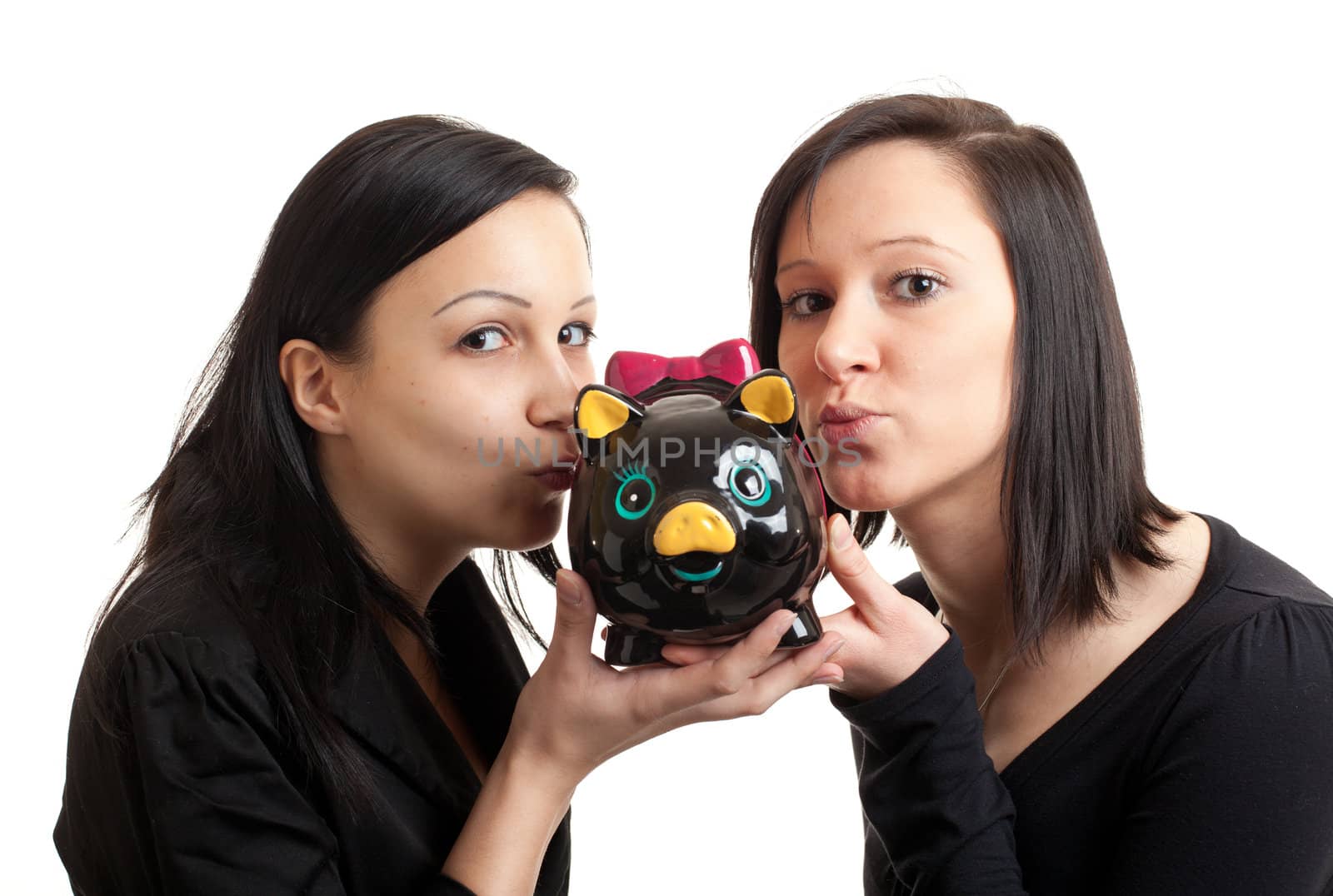 closeup of two young women kissing a piggy bank