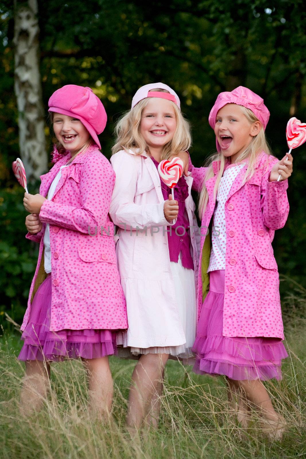 Happy children having pink clothes and a lollipop