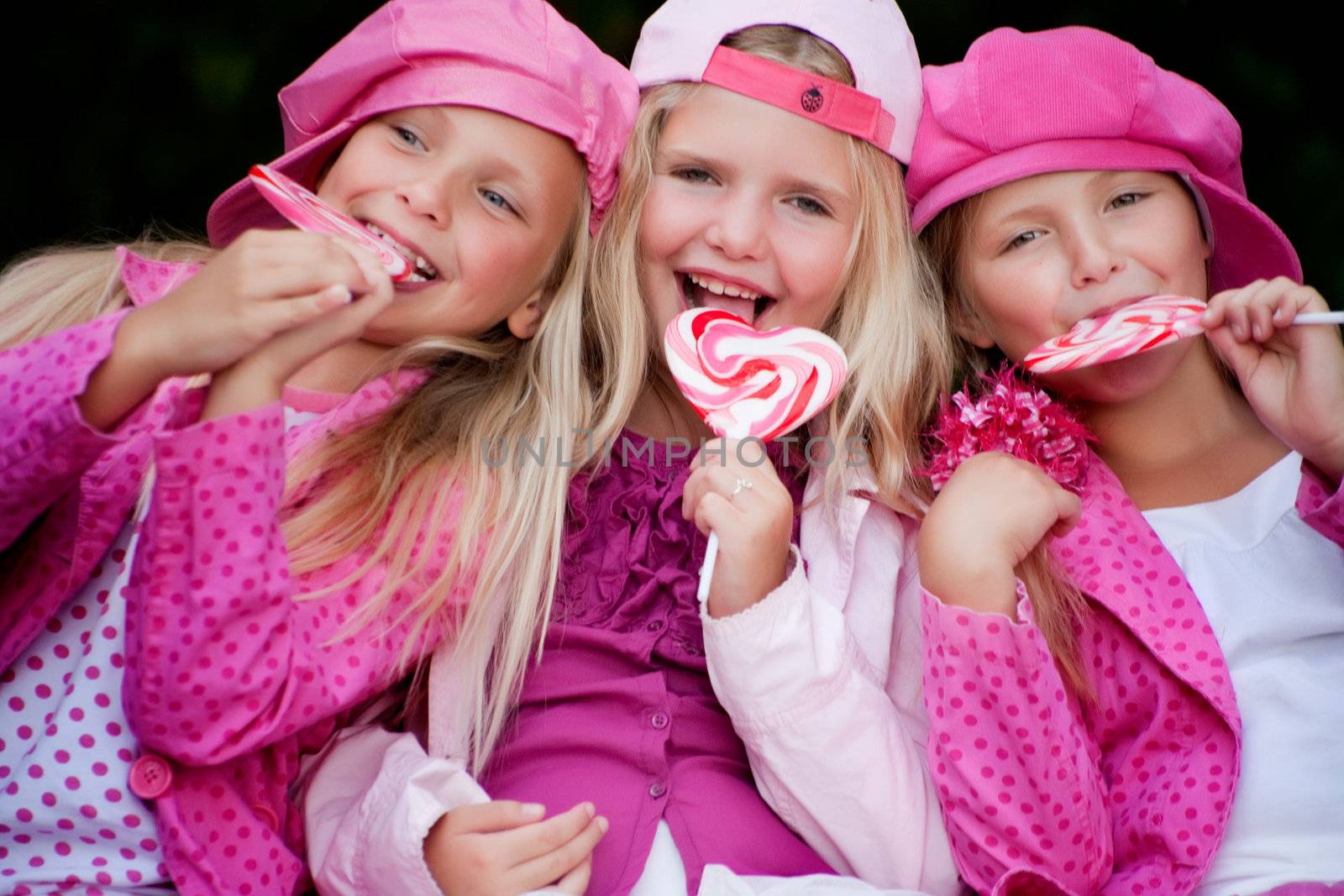 Happy children having pink clothes and a lollipop