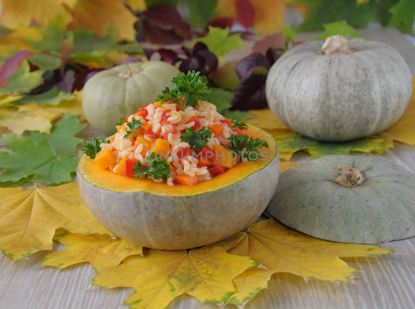 Rice with pumpkin and vegetables in a bowl of pumpkin in the background of autumn leaves