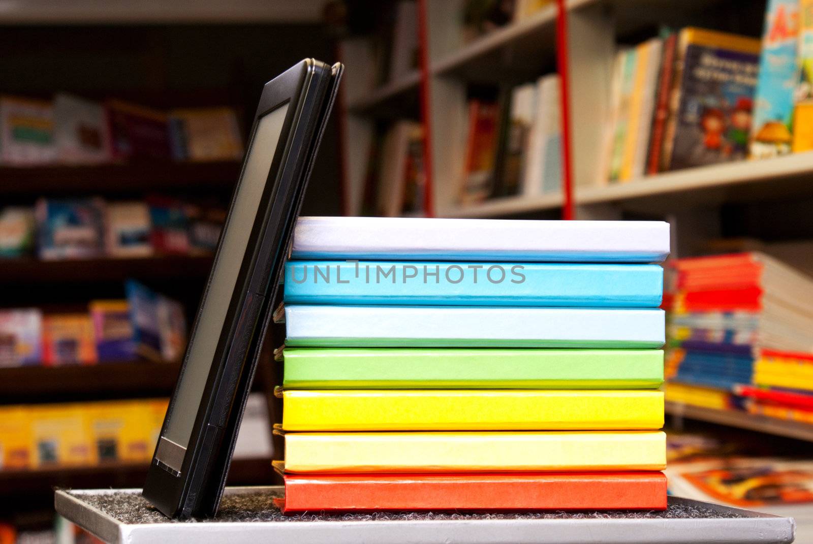 Stack of colorful books with electronic book reader