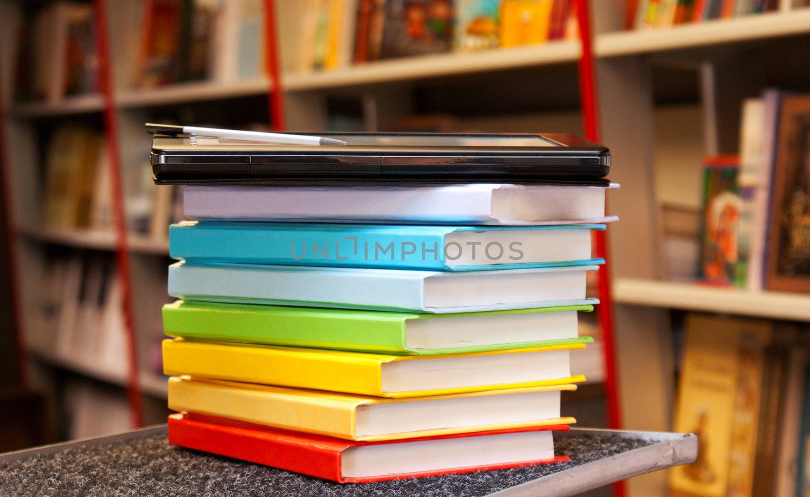 Stack of colorful books with electronic book reader