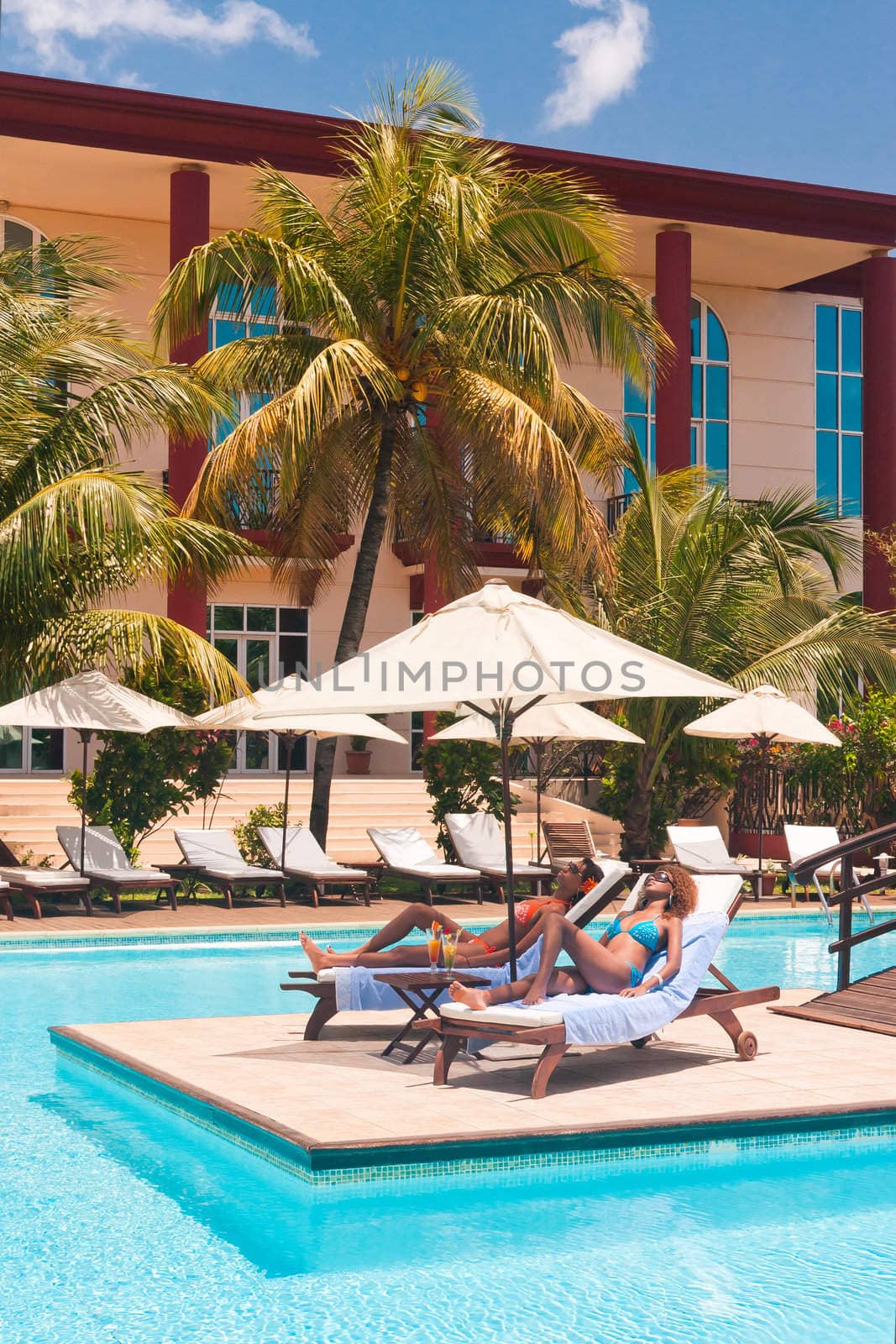 Two women sunbathing on deckchairs by the pool