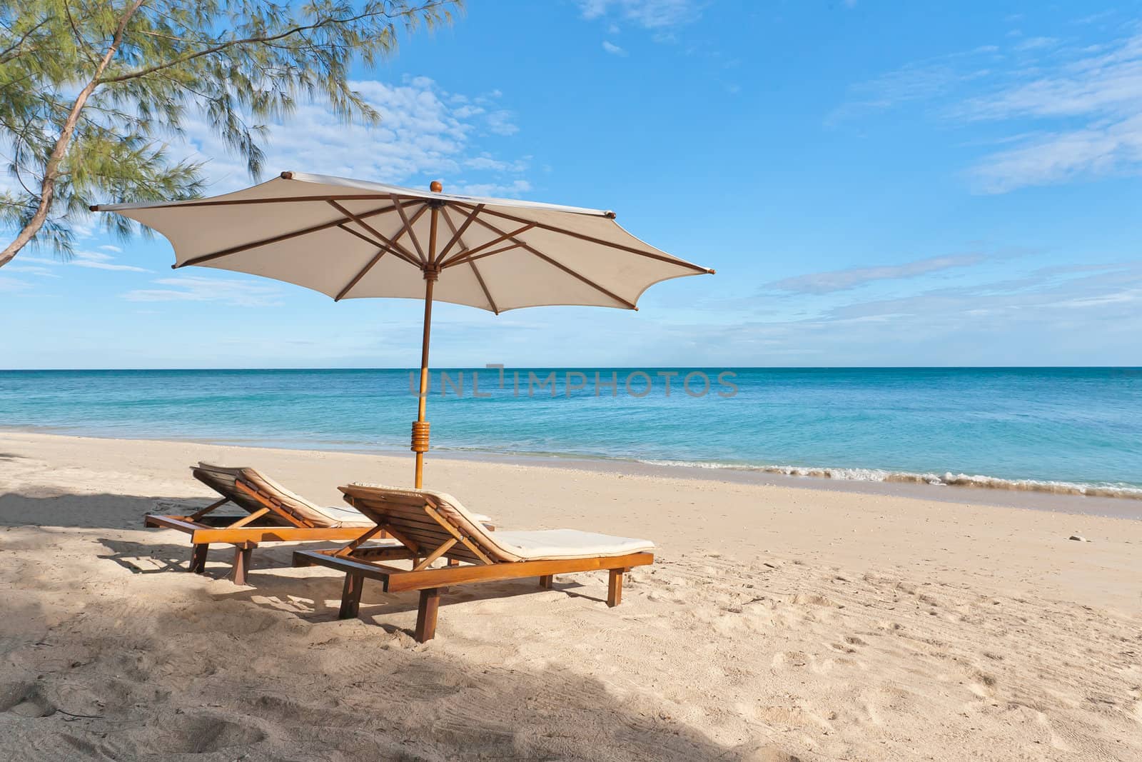 Deckchairs and parasol on the white sand beach facing the lagoon