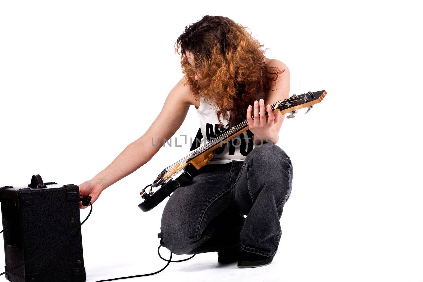 Young girl adjusting her guitar and amplifier