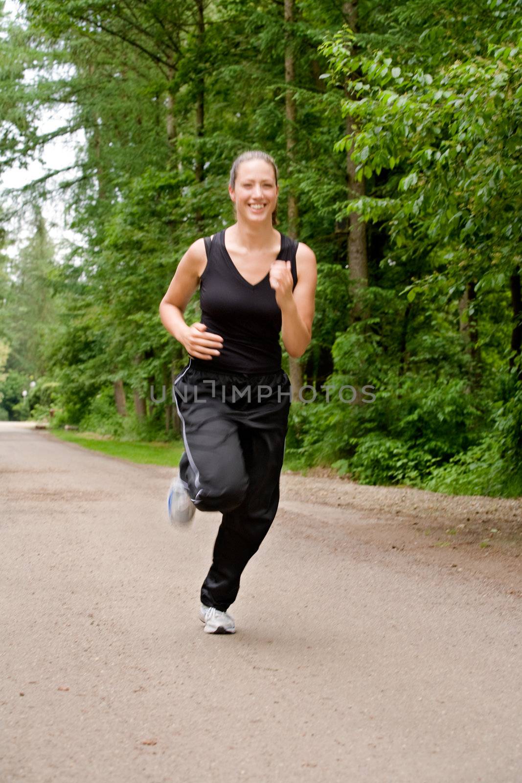 Sportive young woman running over a forrest road by DNFStyle