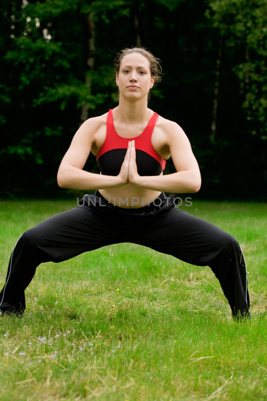 Practising yoga in a green field with trees by DNFStyle