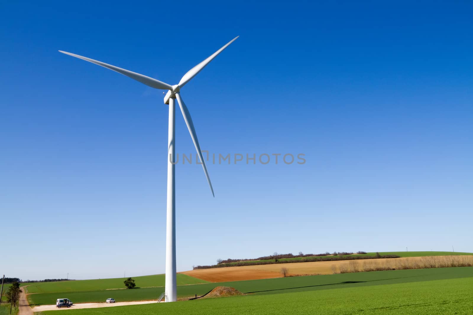 Wind turbine under clear blue sky by chrisroll