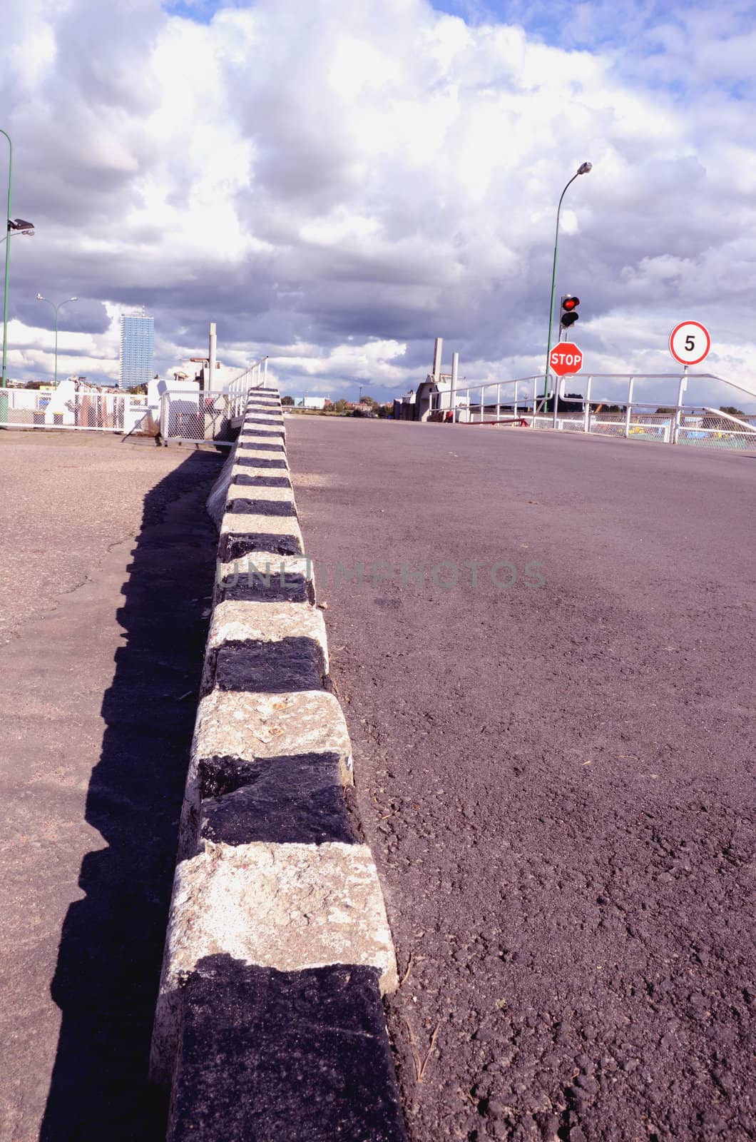 Striped border. Traffic lights and stop sign before the bascule bridge. Cloudy sky.