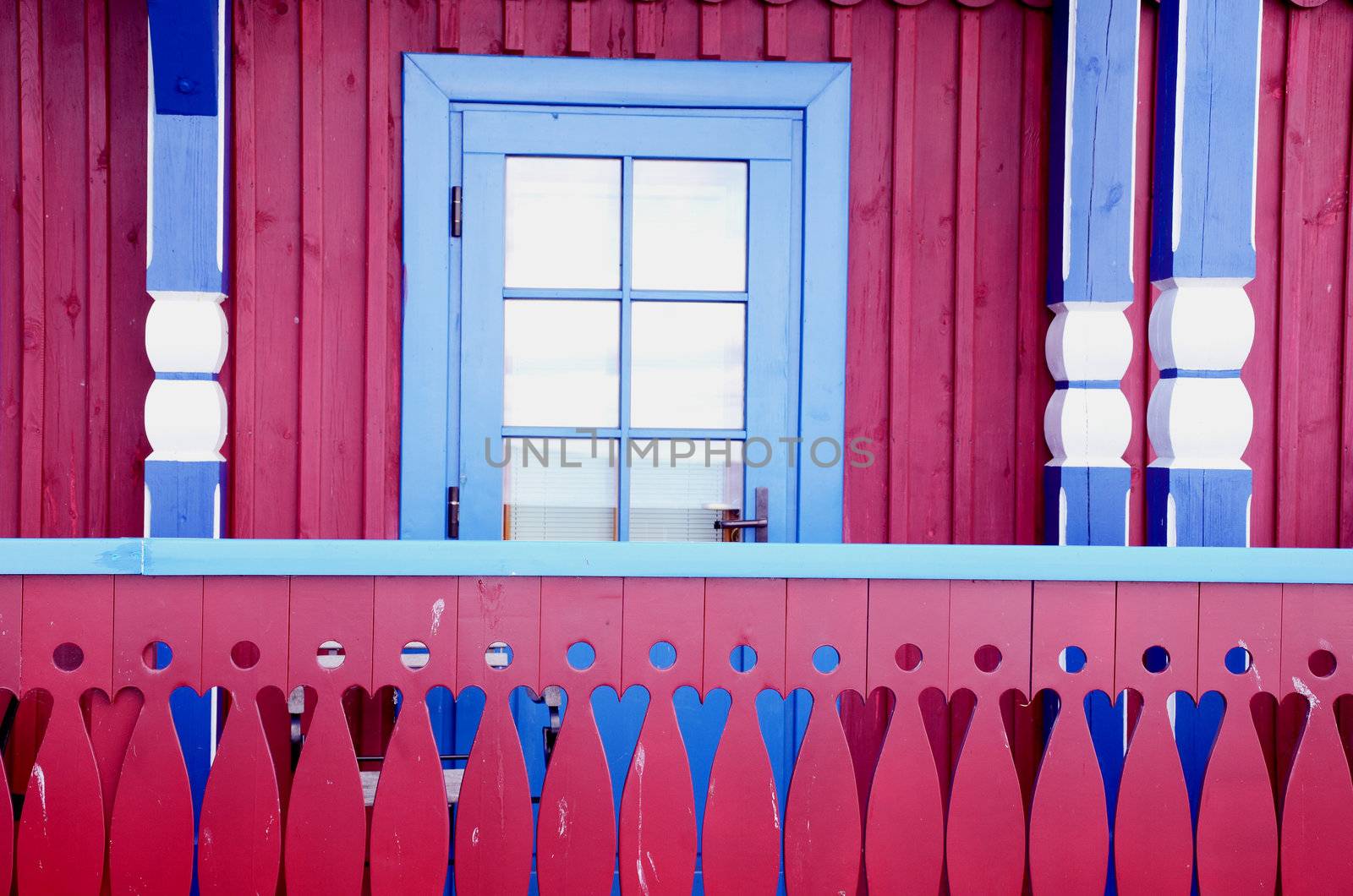 Red wooden cottage with blue accents. The architectural centerpiece.