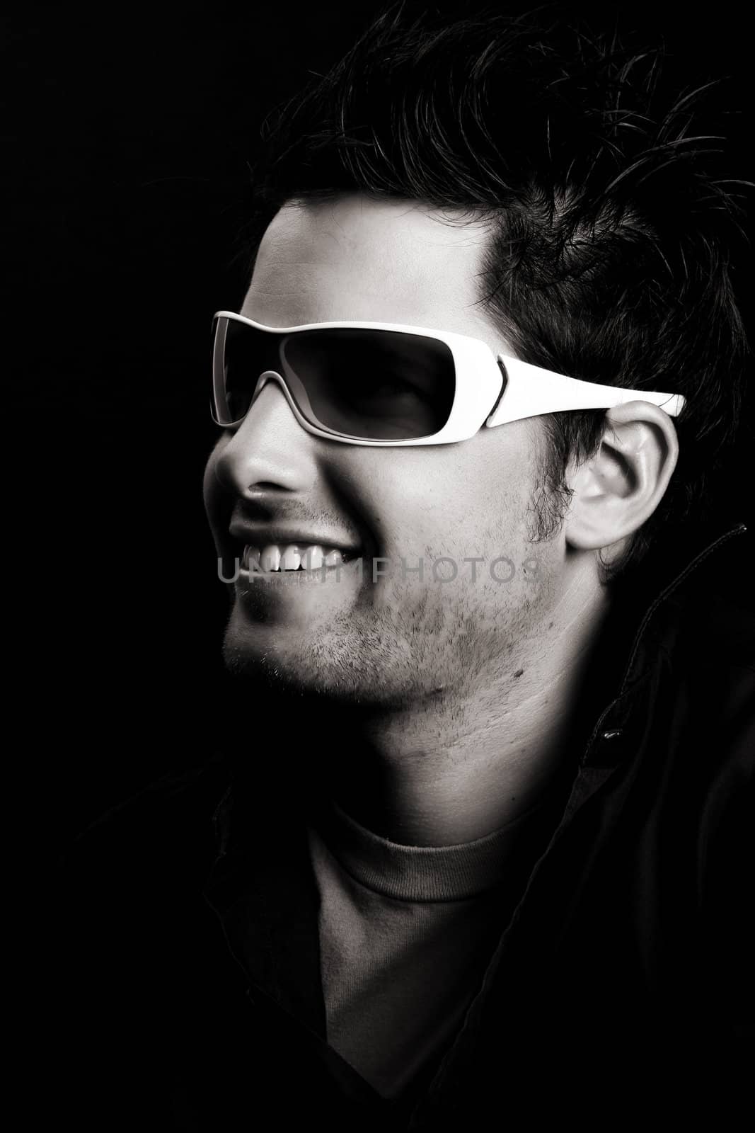 Attractive male wearing sunglasses against black background