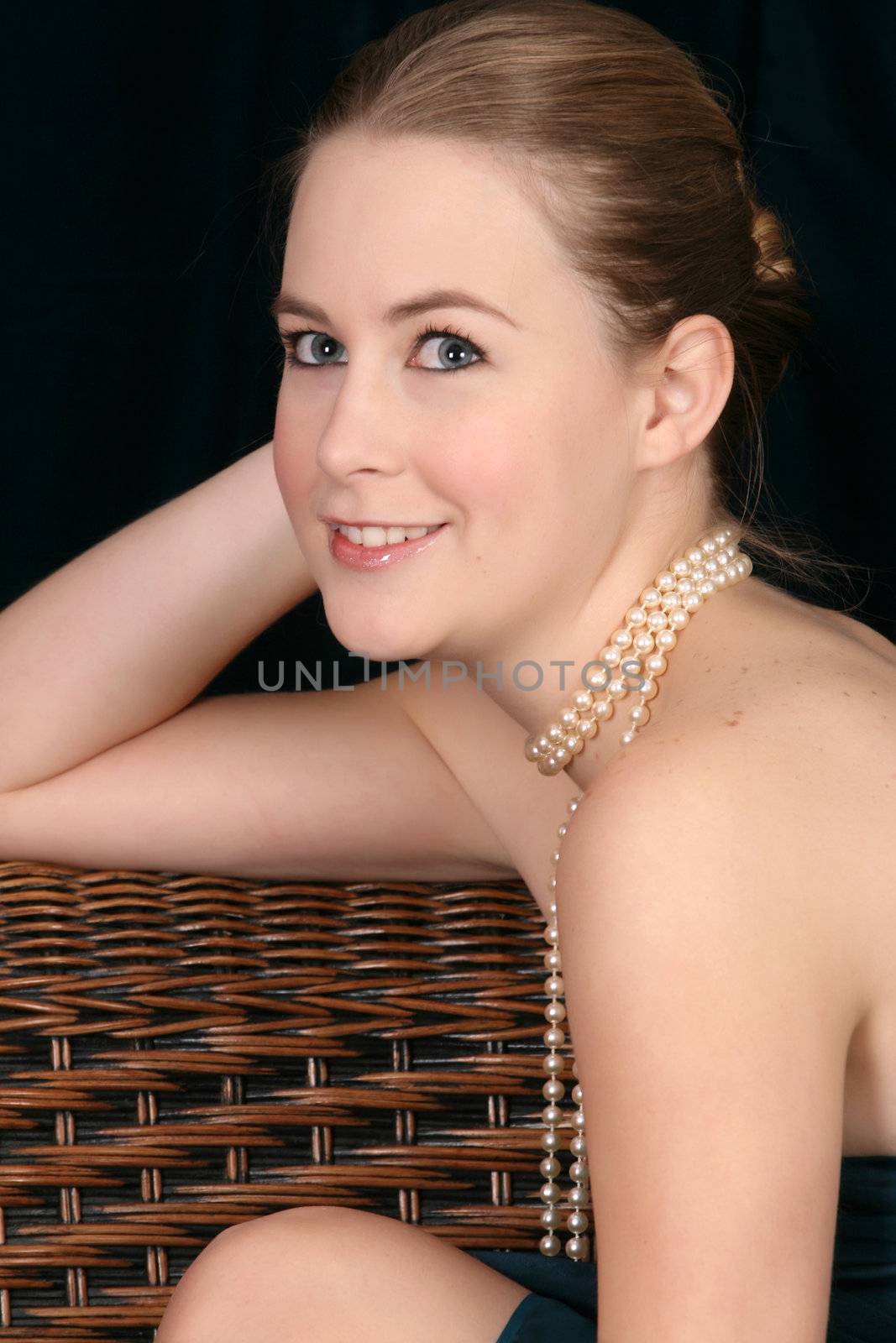 Beautiful blond female wearing pearls against a dark background