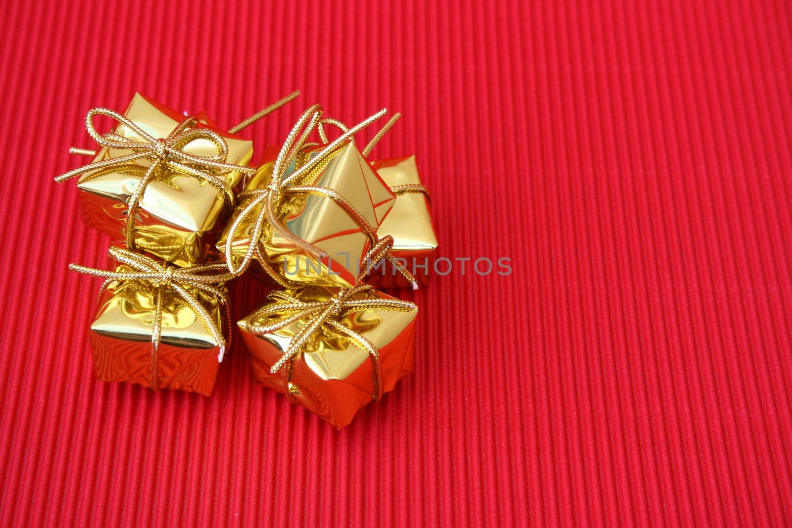 Small golden christmas gifts on a red background
