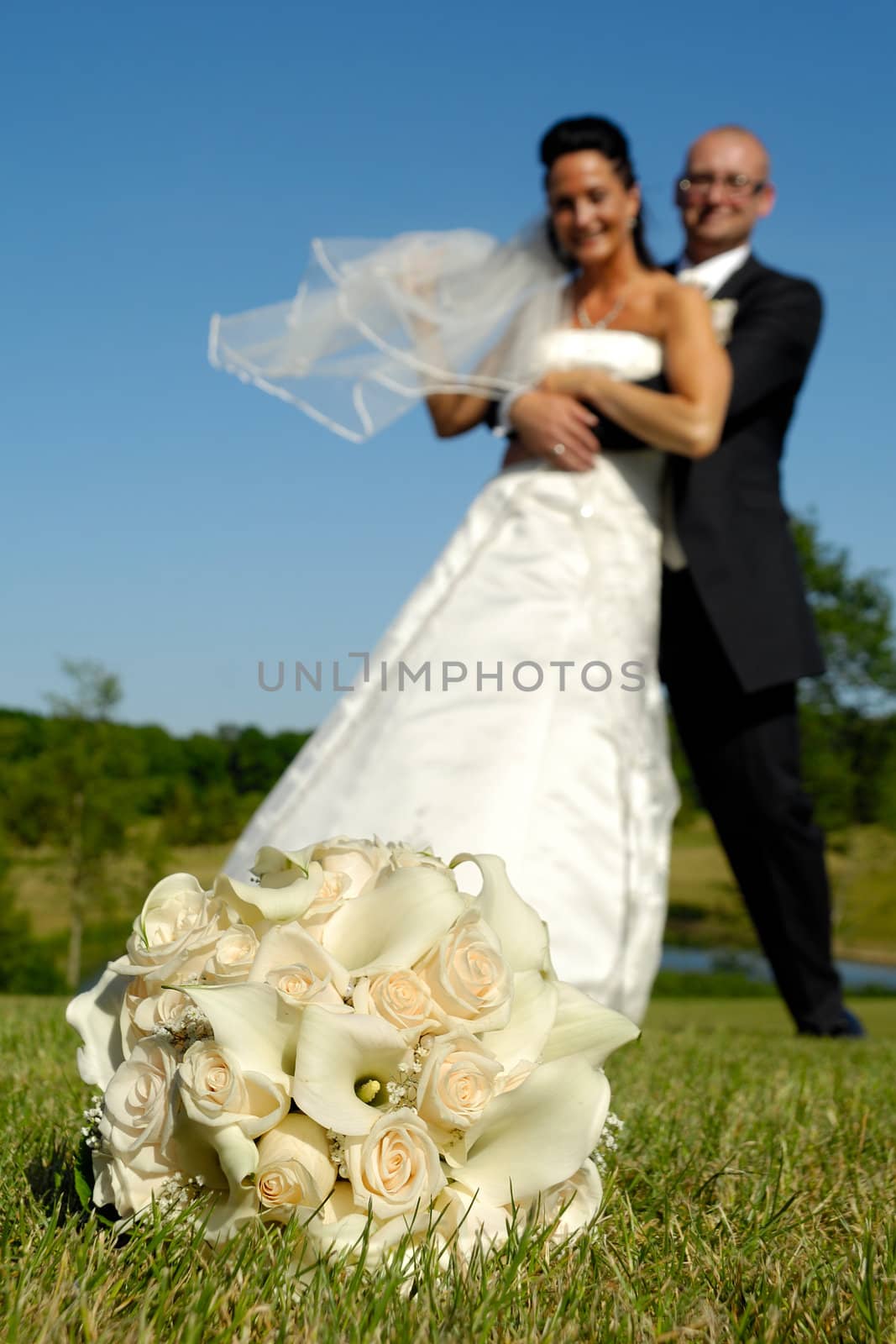 Wedding bouquet in focus and couple in blur