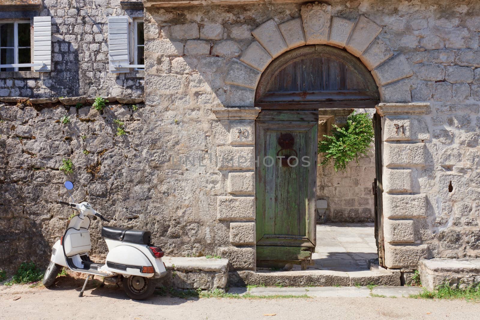 White moped next to broken old wooden gates