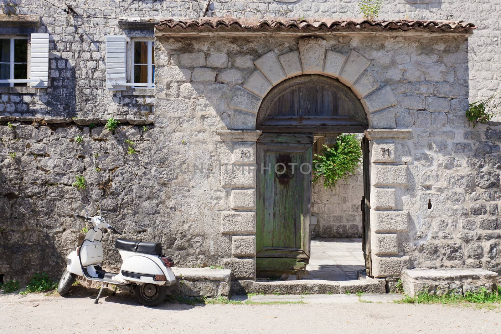 White moped next to broken old wooden gates