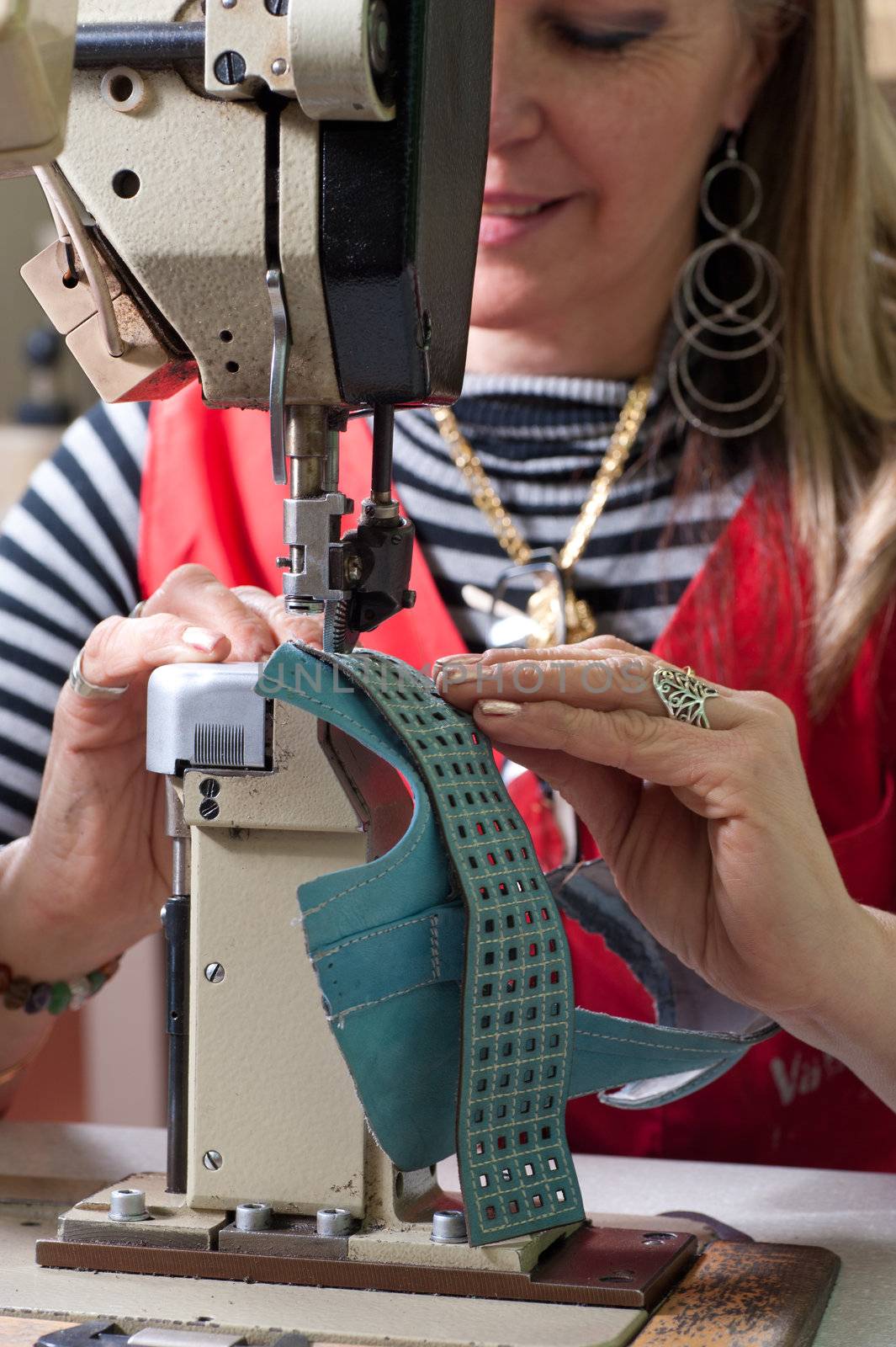 Female worker sewing leather in a footwear factory