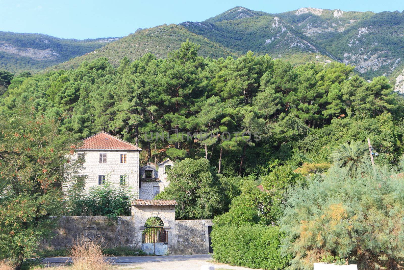 Traditional stone house in trees at the foot of a mountain