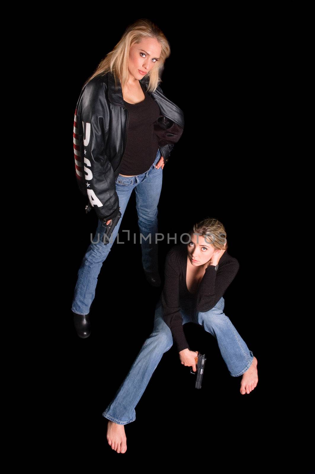 two young women with semiautomatic firearms one in a black leather jacket with USA on the arm, over a black background