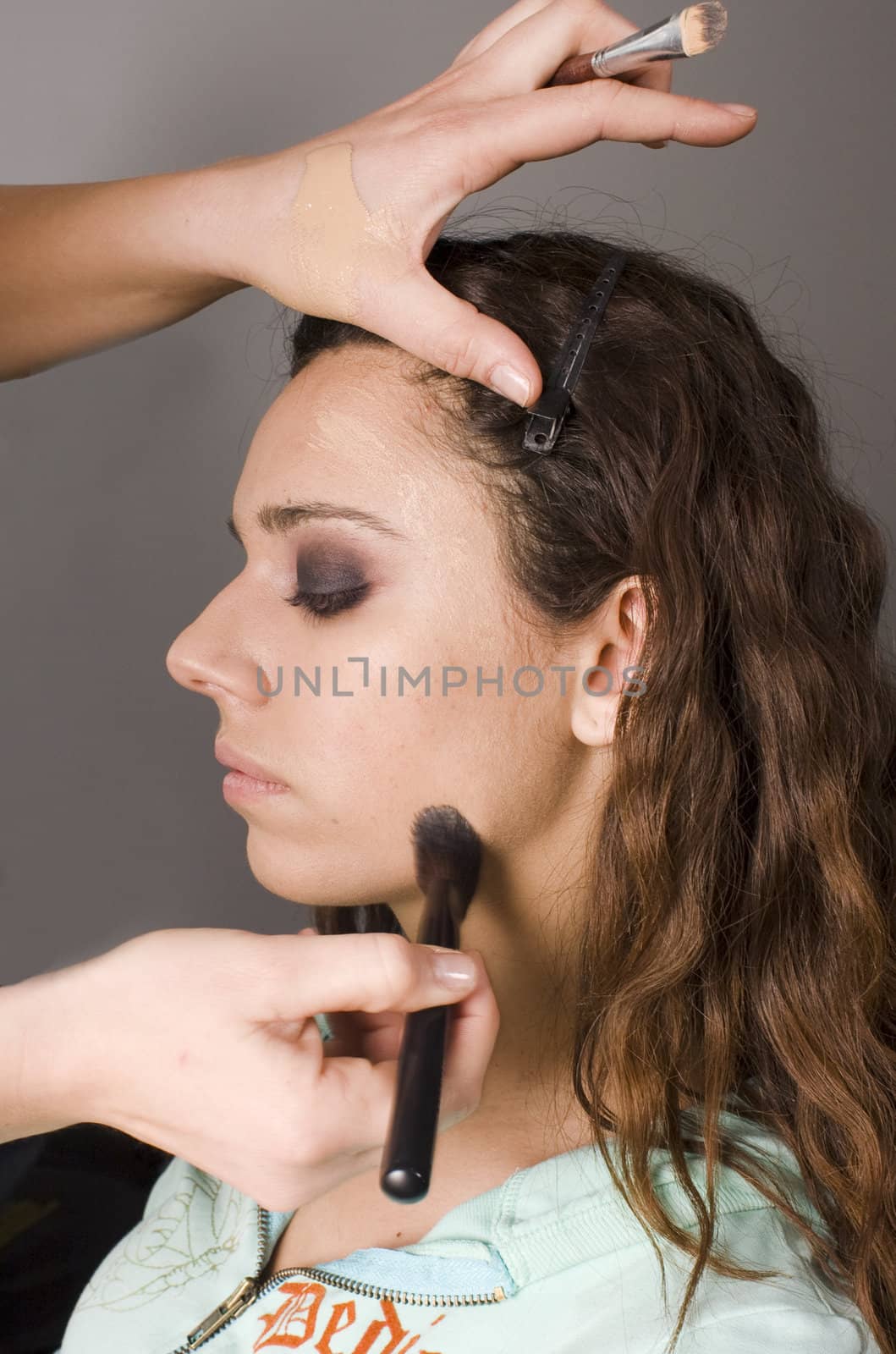 closeup of makeup artist applying base foundation to model