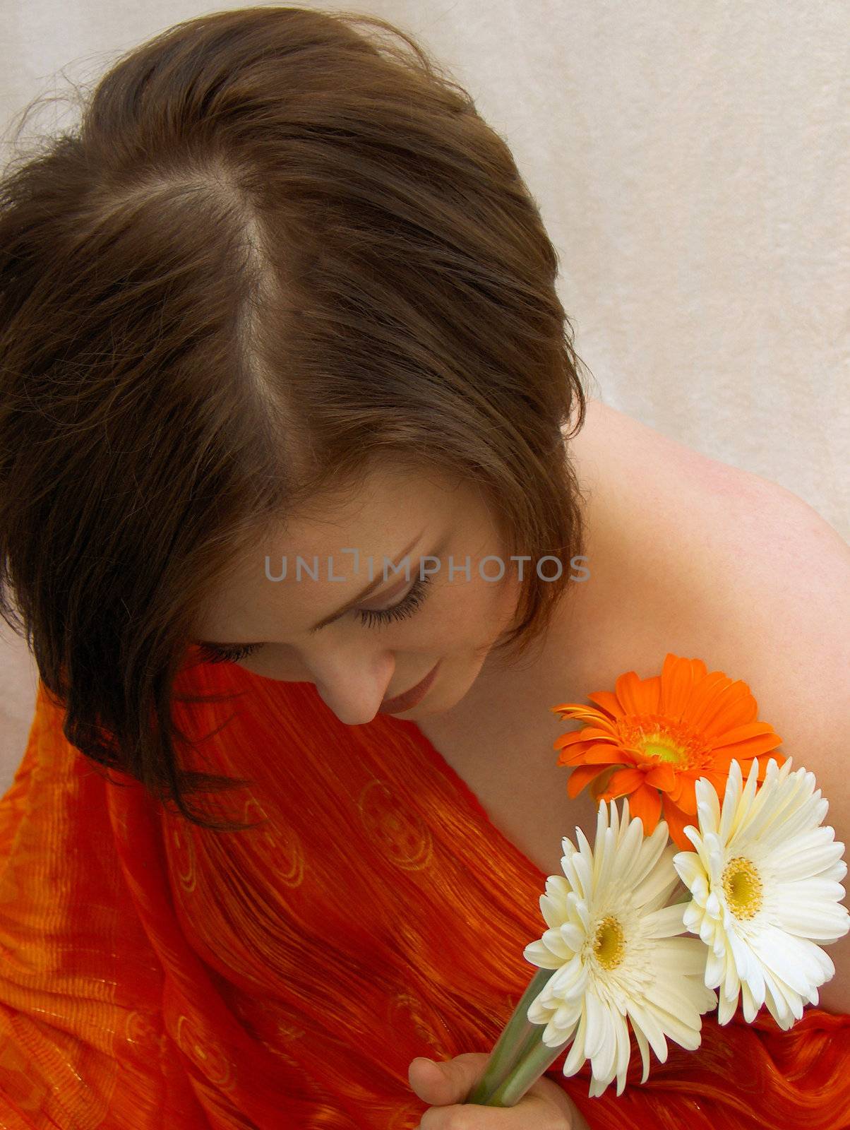 A beautiful brunette, wearing red, with a bouquet of daisies, looking down demurely.