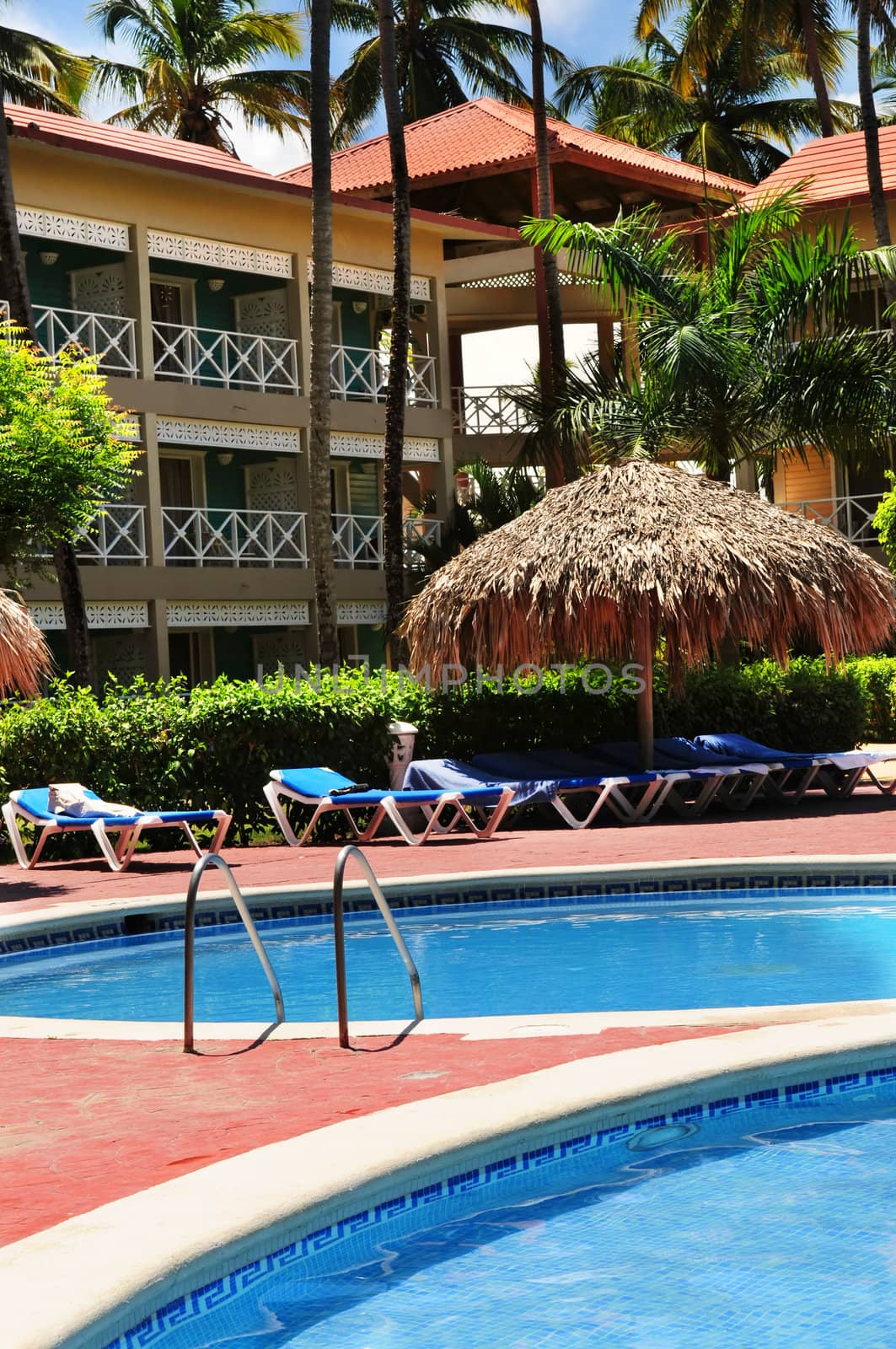 Swimming pool and hotel with palm trees at tropical resort