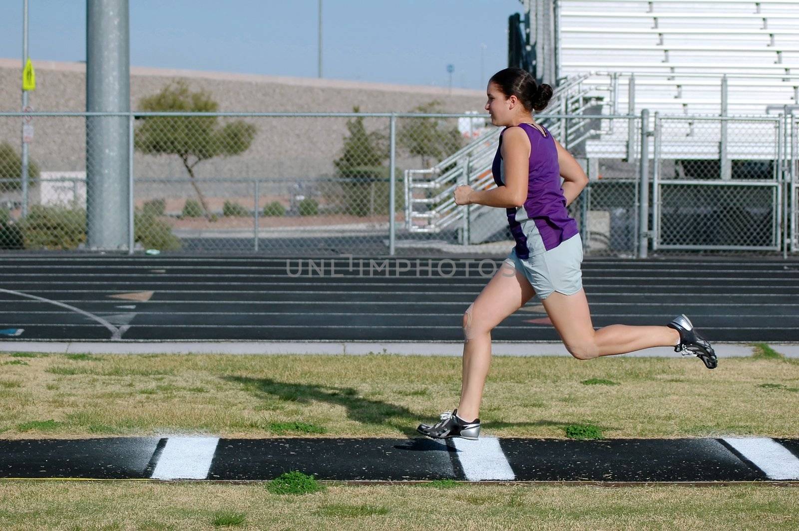 Teenage girl practicing long jump                            