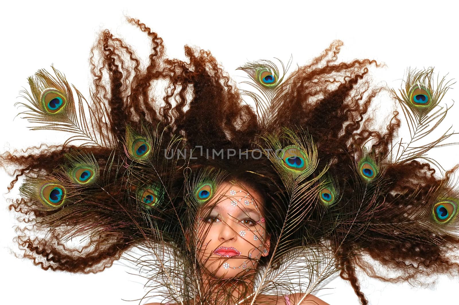 Girl wearing makeup made of rhinestone flowers with peacock feathers in her hair         